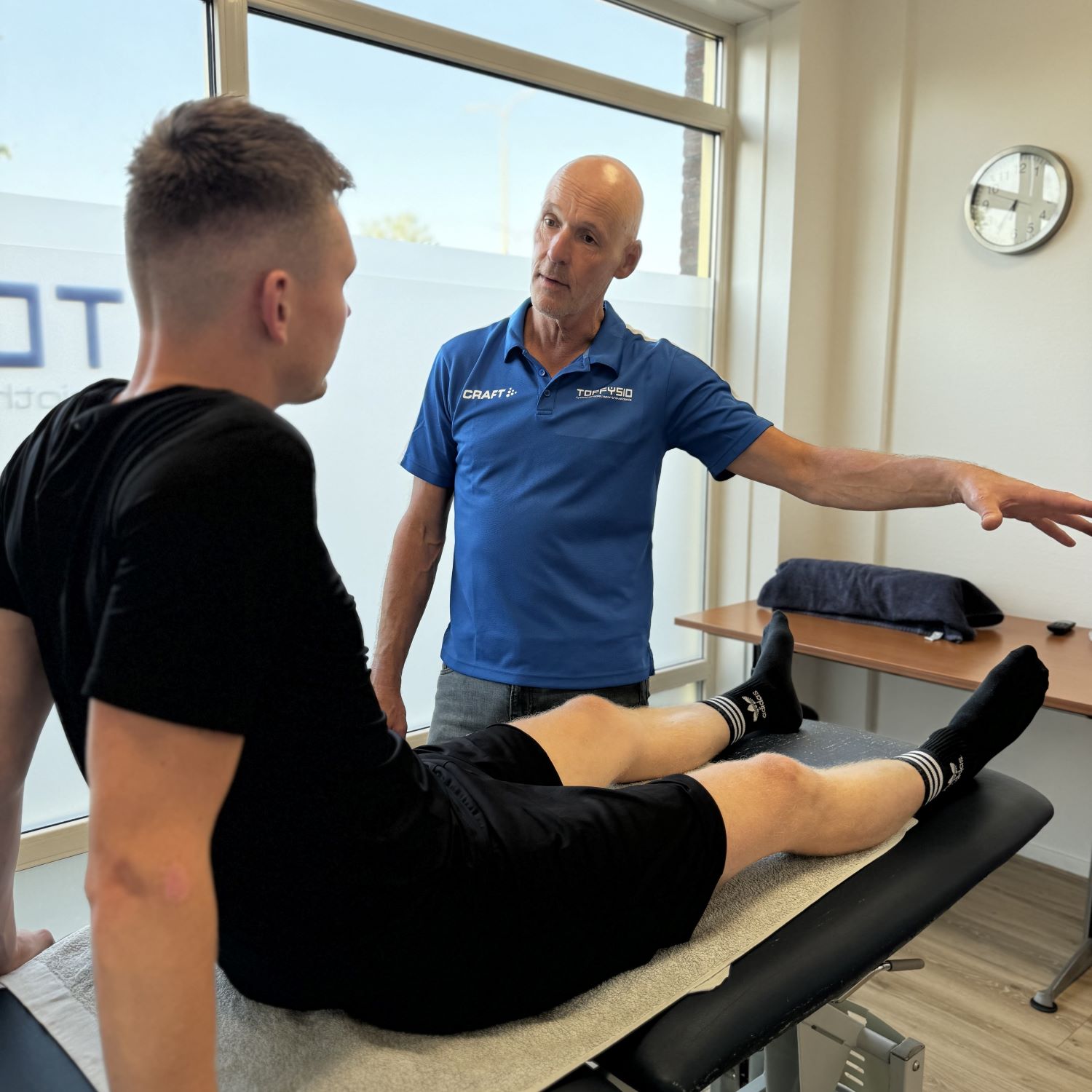 fysiotherapeut legt compartimentsyndroom in onderbeen uit aan sporter tijdens behandeling
