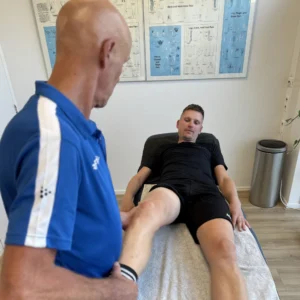 Fysiotherapeut onderzoekt pijn aan de buitenkant van de knie bij een hardloper