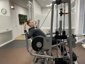 Patiënt traint na ischias de rugspieren op de OriGENE bij TopFysio Leeuwarden.