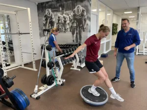 Fysiotherapeut begeleidt een voetbalster tijdens training bij voorste kruisbandletsel bij vrouwen